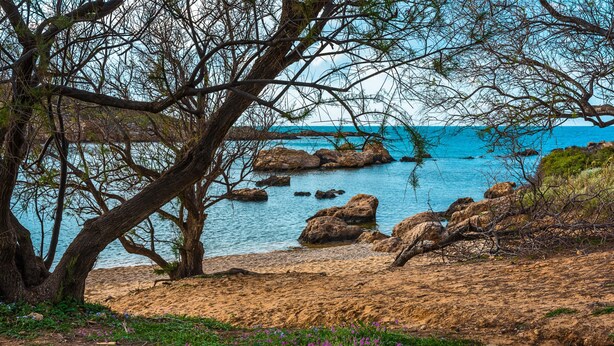 A coastal landscape with rocky terrain, a sandy beach, and a clear blue sea. - Thea Artemis (Chania)