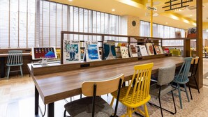 A modern library with wooden tables, chairs, and bookshelves.