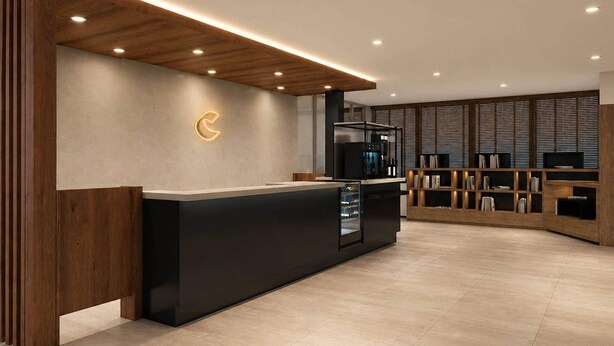A modern reception area with a wooden reception desk, a wall-mounted logo, and a built-in bookshelf.