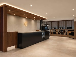 A modern reception area with a wooden reception desk, a wall-mounted logo, and a built-in bookshelf. - Comfort Hotel ERA Nagoya Meiekiminami (Nagoya)