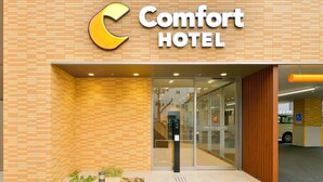 A hotel entrance with a tiled facade, a glass door entrance, and a wheelchair-accessible ramp.