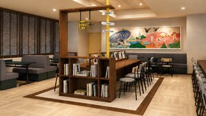 A modern library with a central bookshelf, seating areas, and a colorful mural on the wall.