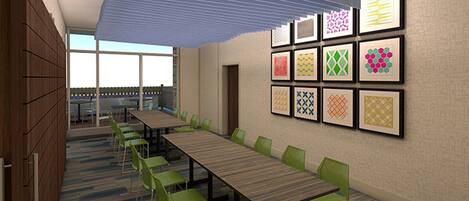 A conference room with a long table, green chairs, and framed patterns on the wall.