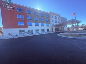 Un bâtiment de la chaîne Holiday Inn Express & Suites, doté d’une architecture moderne, d’une entrée couverte et d’un mât sur lequel flotte le drapeau américain.