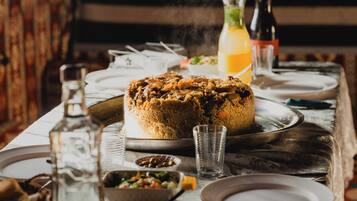 A dining table with a large cake, glasses, and bottles.