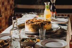 Una mesa de comedor con un pastel grande, vasos y botellas.