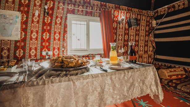 Un comedor con una mesa dispuesta para una comida, paredes con diseño, una ventana y un mapa en la pared.
