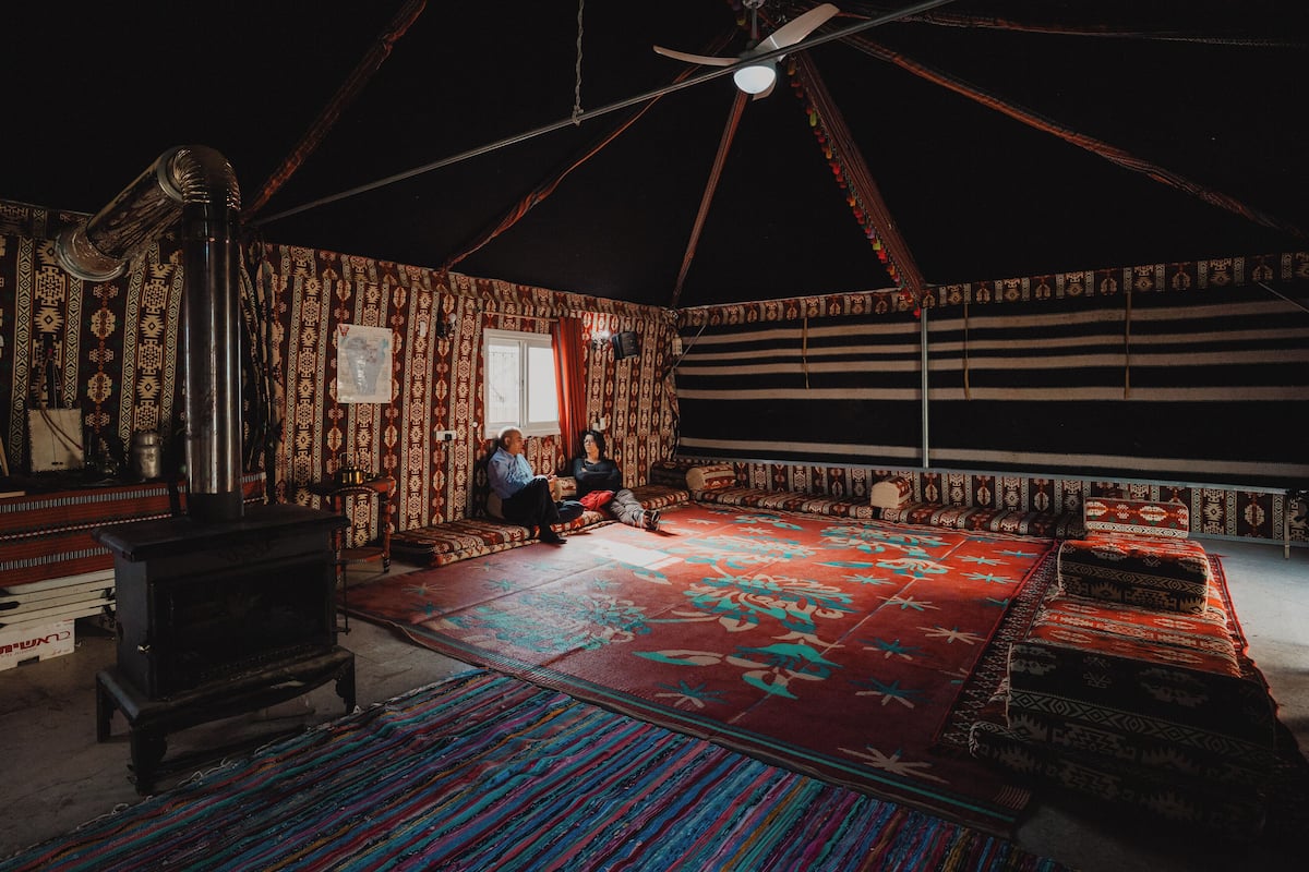 A room with patterned walls, a large rug, a sofa, and a traditional stove.