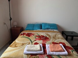 A bed with a floral bedspread, two pillows, and two folded towels.