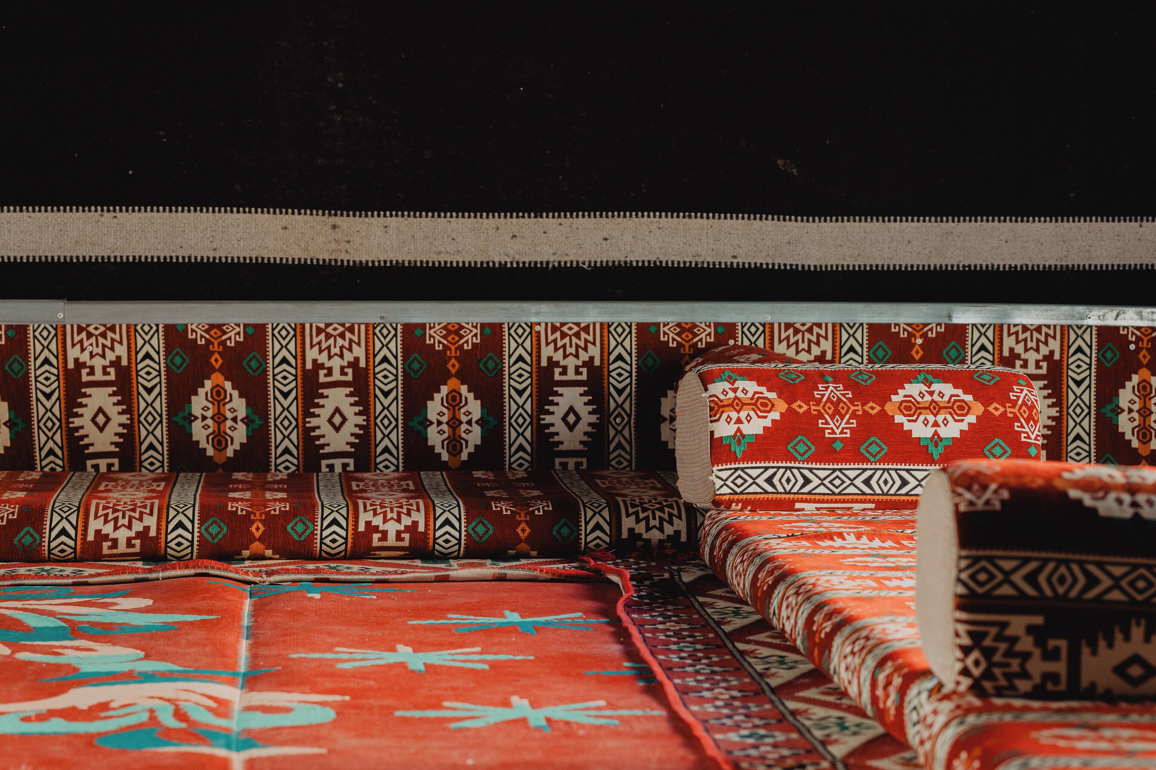 Un canapé traditionnel agrémenté de coussins à motifs et d’un tapis rouge aux dessins géométriques.