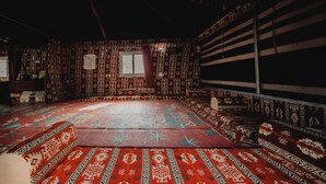 Una habitación con paredes con diseño, un tapete grande en el centro y una ventana con cortinas.