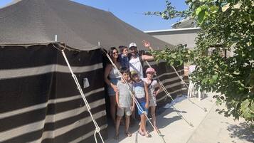 A group of people standing in front of a striped tent-like structure.