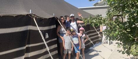 Un grupo de personas frente a una estructura con forma de carpa a rayas.