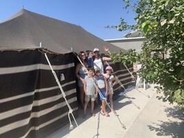 Un grupo de personas frente a una estructura con forma de carpa a rayas.