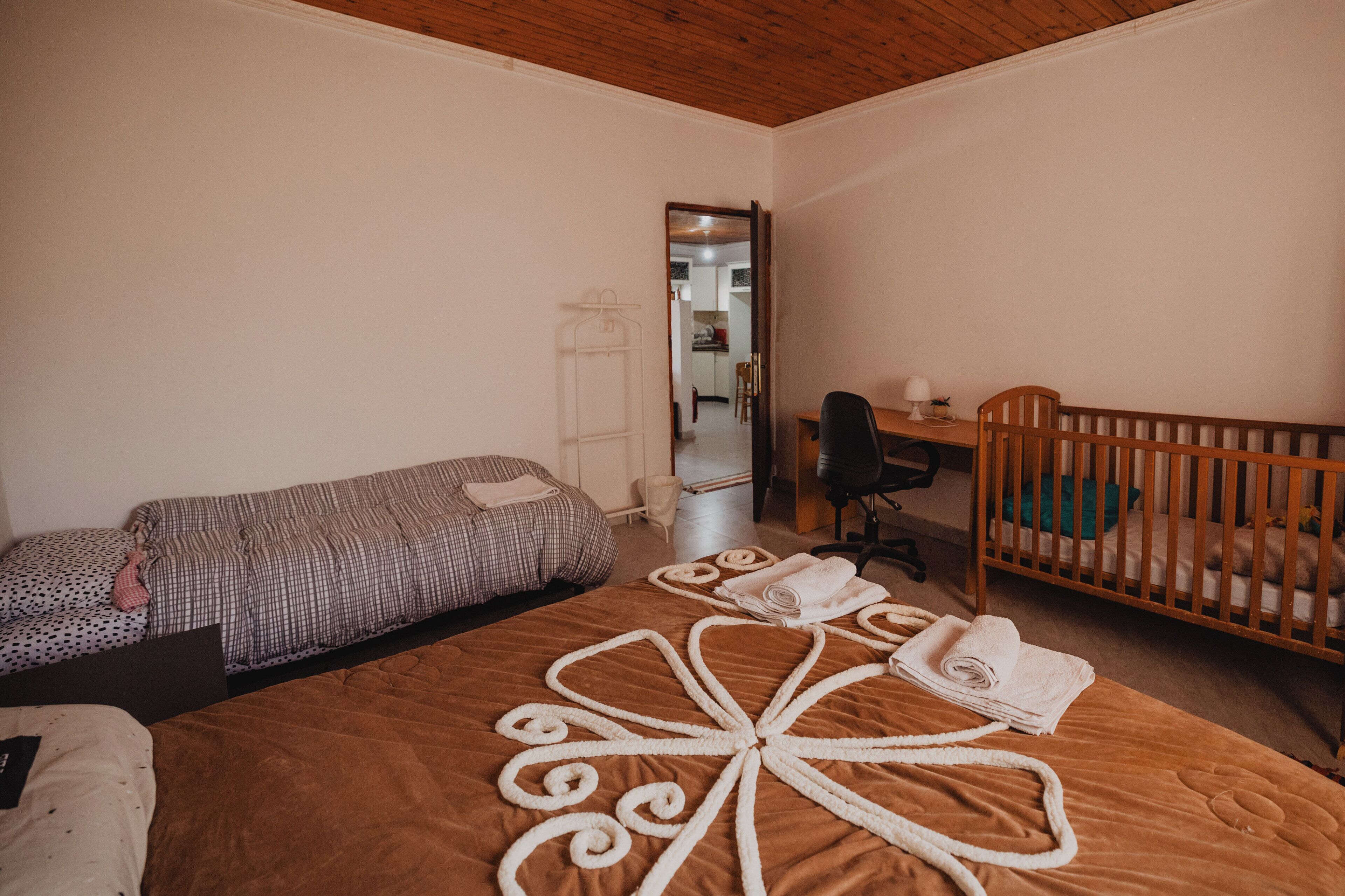 Un dormitorio con una cama, una cuna, un escritorio y una silla.