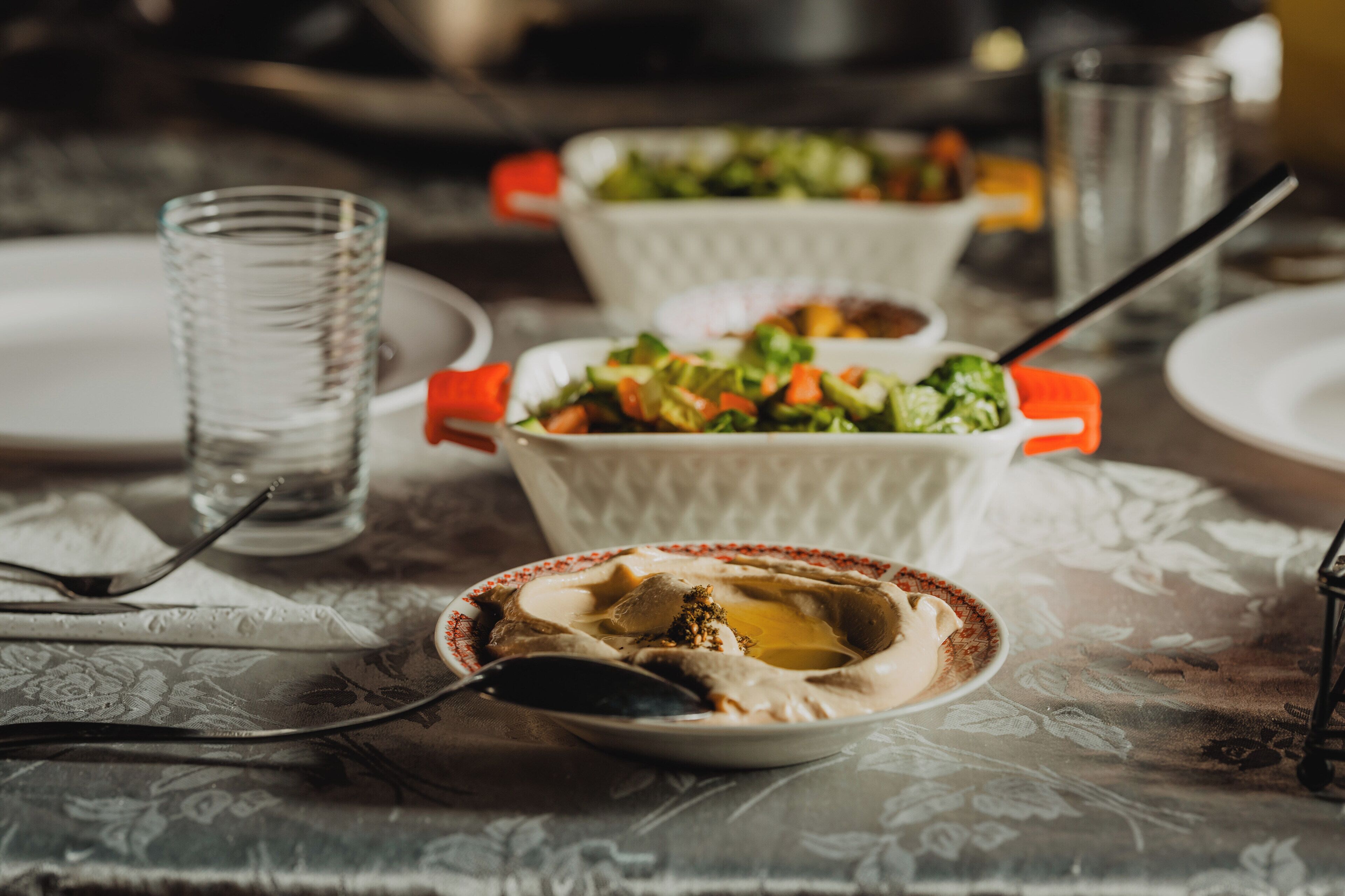 Une table à manger avec un verre d’eau, un saladier et une assiette avec une cuillère.