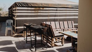 Un espacio de estar techado al aire libre con un sofá a rayas, una mesa de madera y una silla.