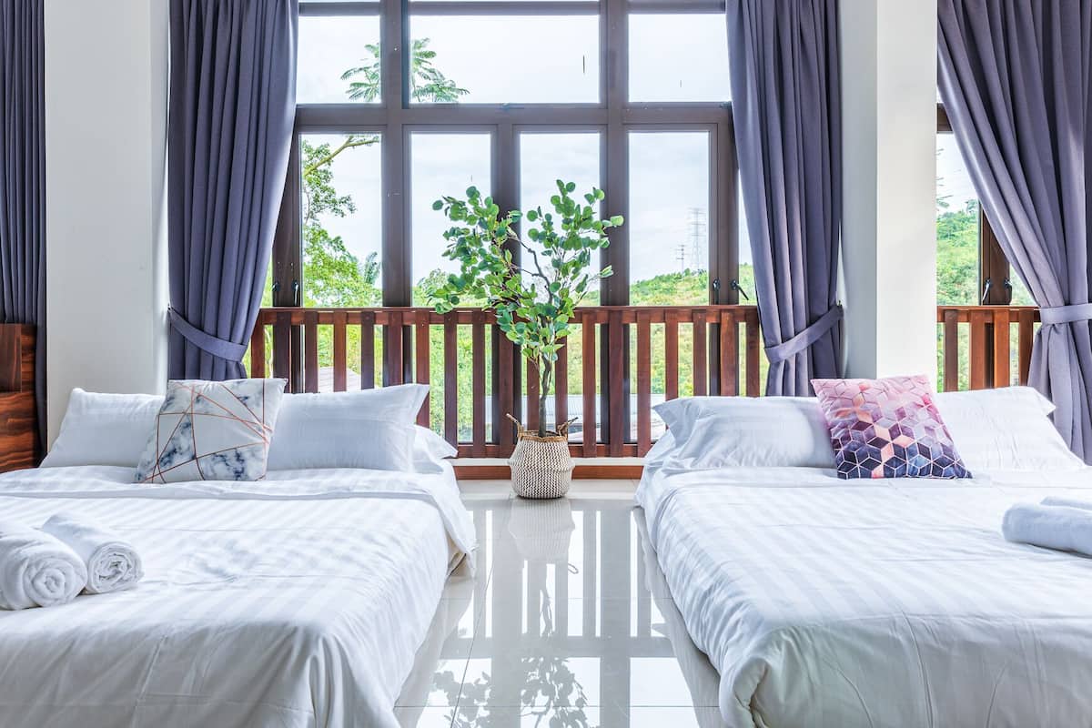 A hotel room with two beds, large windows, a wooden deck, and a potted plant.