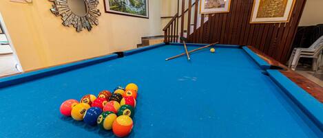 A pool table with colorful balls, a mirror, and framed artwork on the walls.