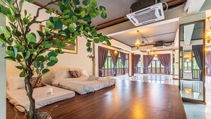 A spacious room with a large bed, a small sofa, and a potted plant. - Bentong Eco Wellness Resort (Raub)