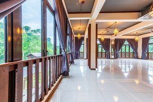 Amplia habitación de hotel con ventanas grandes, barandillas de madera y múltiples lámparas colgantes.