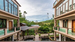 A modern building with a central courtyard, stone pillars, and a small bridge. - Bentong Eco Wellness Resort (Raub)