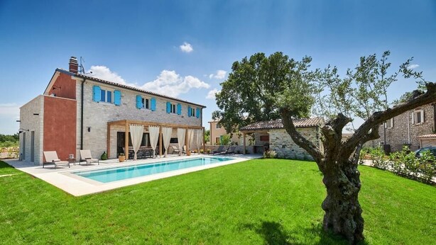 A two-story house with a swimming pool, a tree in the yard, and a stone wall. - Villa Celeste (Umag)