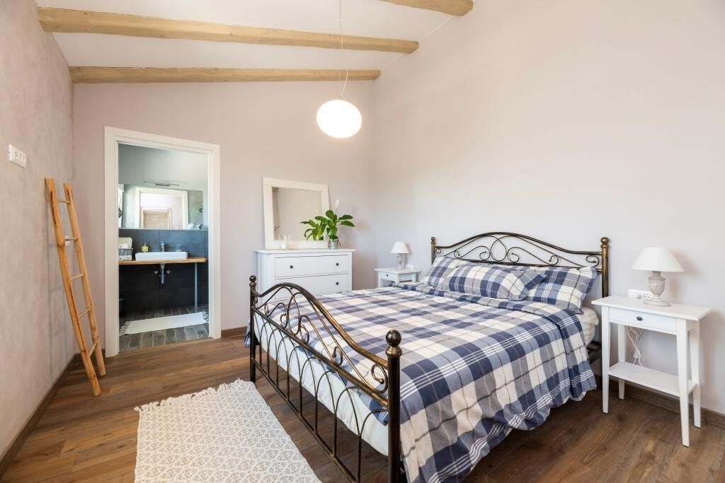 A bedroom with a bed, bedside tables, a mirror, and a wooden ladder.