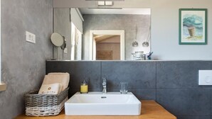 A modern bathroom with a large mirror, a white sink, and a wooden countertop. - Villa Celeste (Umag)