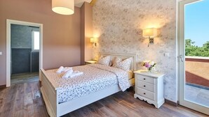 A bedroom with a bed, bedside tables, a nightstand, a window, and a door. - Villa Celeste (Umag)