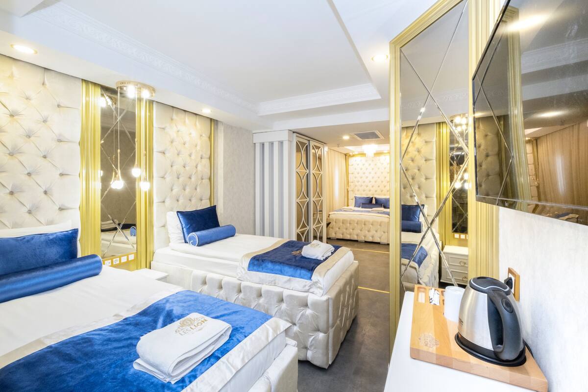 Une chambre d’hôtel avec deux lits, un grand miroir et une machine à café posée sur une table d’appoint en bois.