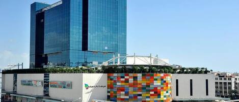 Un bâtiment moderne doté d’une façade en verre et d’un mur décoré d’une mosaïque aux couleurs vives.