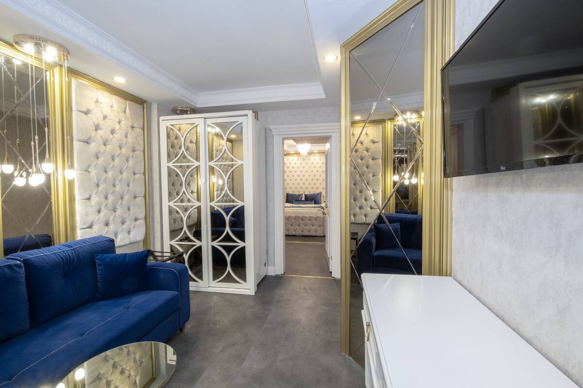Un salon moderne avec un canapé bleu, une table basse blanche et un mur miroir.