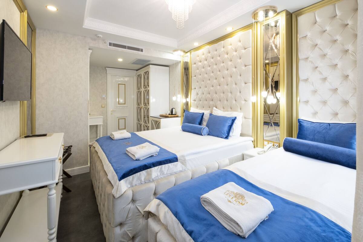 Une chambre d’hôtel avec deux lits, un bureau et une télévision.