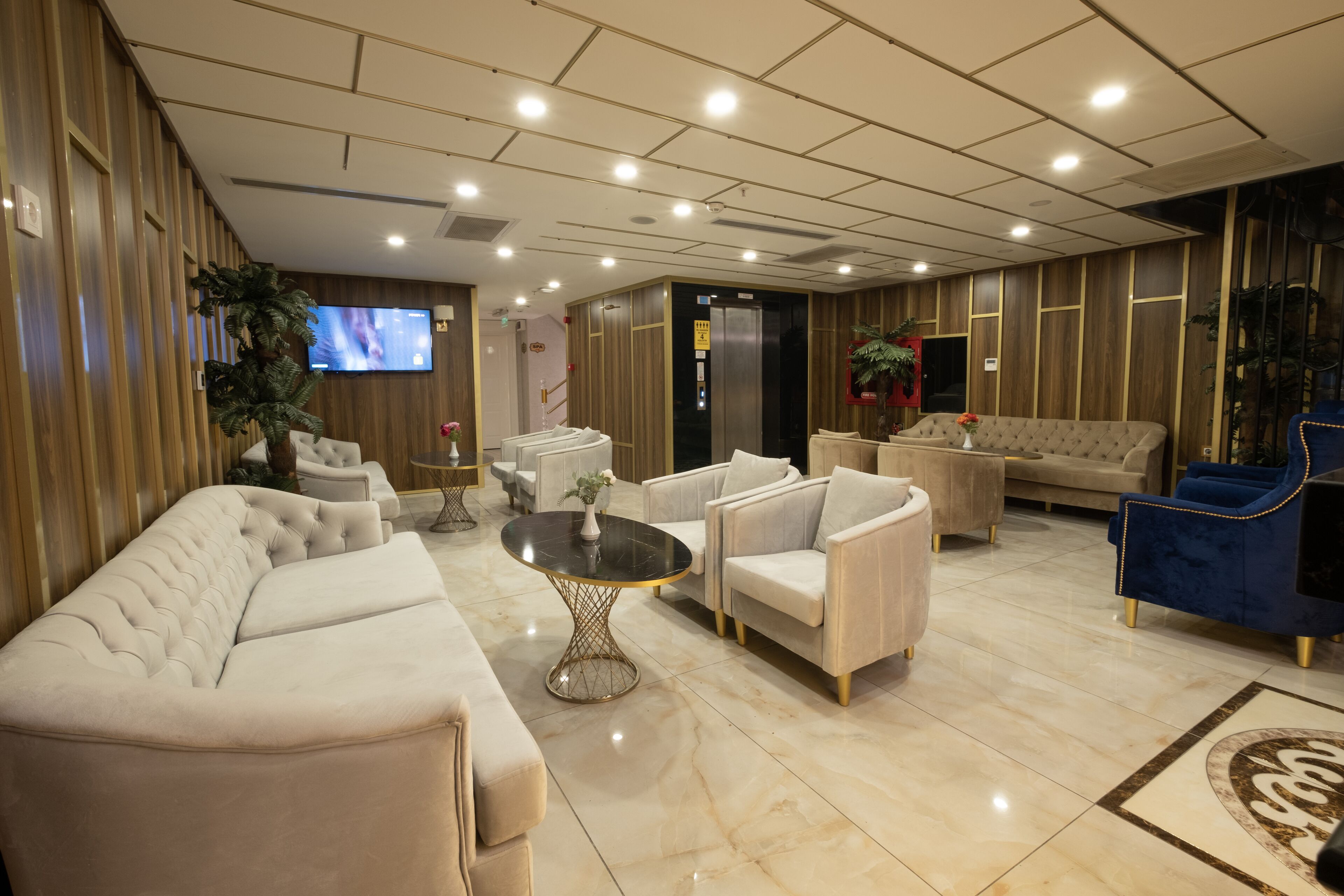 Un hall amplio con diseño moderno, que incluye un sofá grande, sillones, una mesa de centro y una pantalla de televisión.