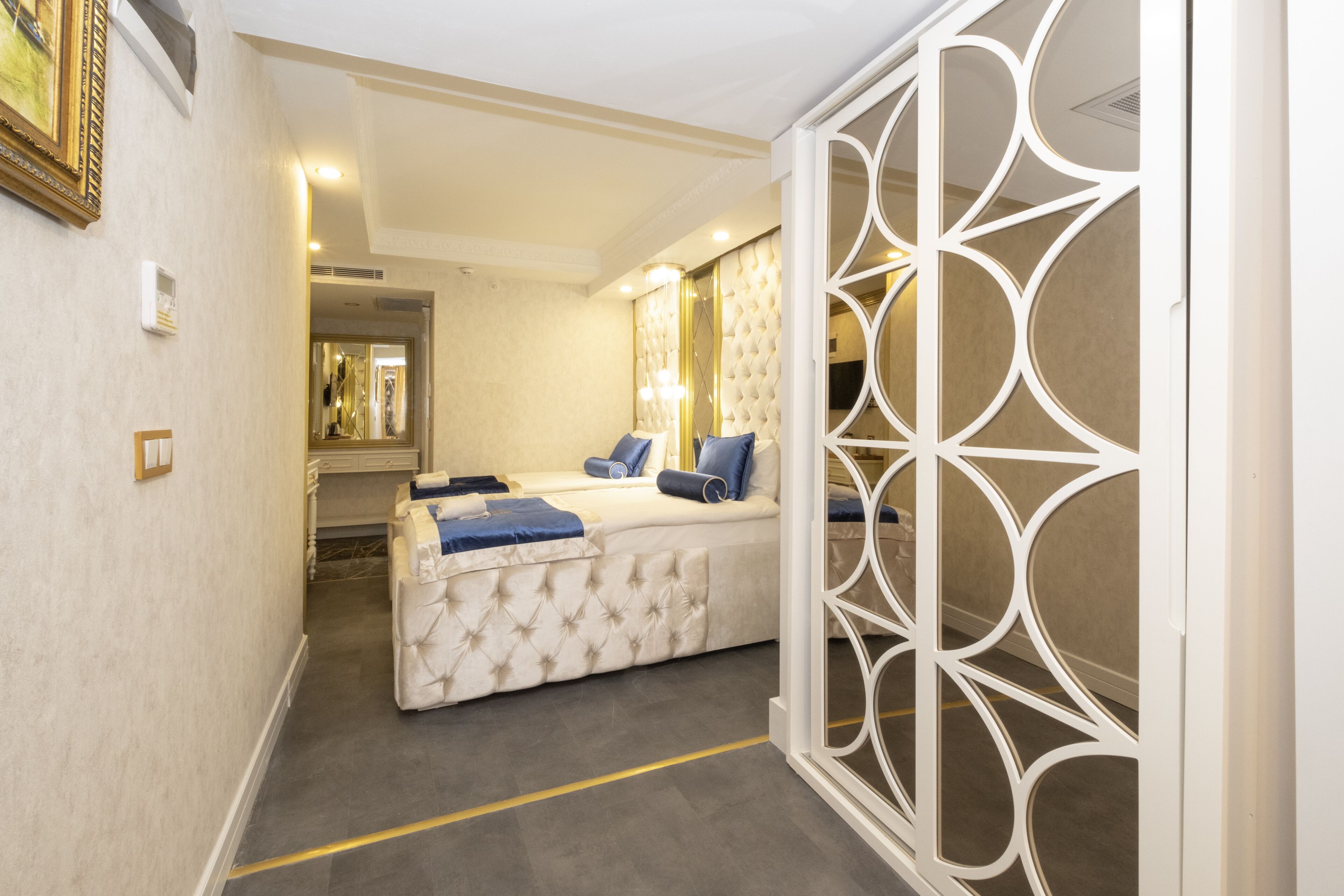 A bedroom with a bed, a decorative screen, and a mirror.