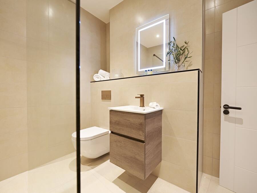 Et moderne badeværelse med toilet, vaskebord med spejl og en plante.