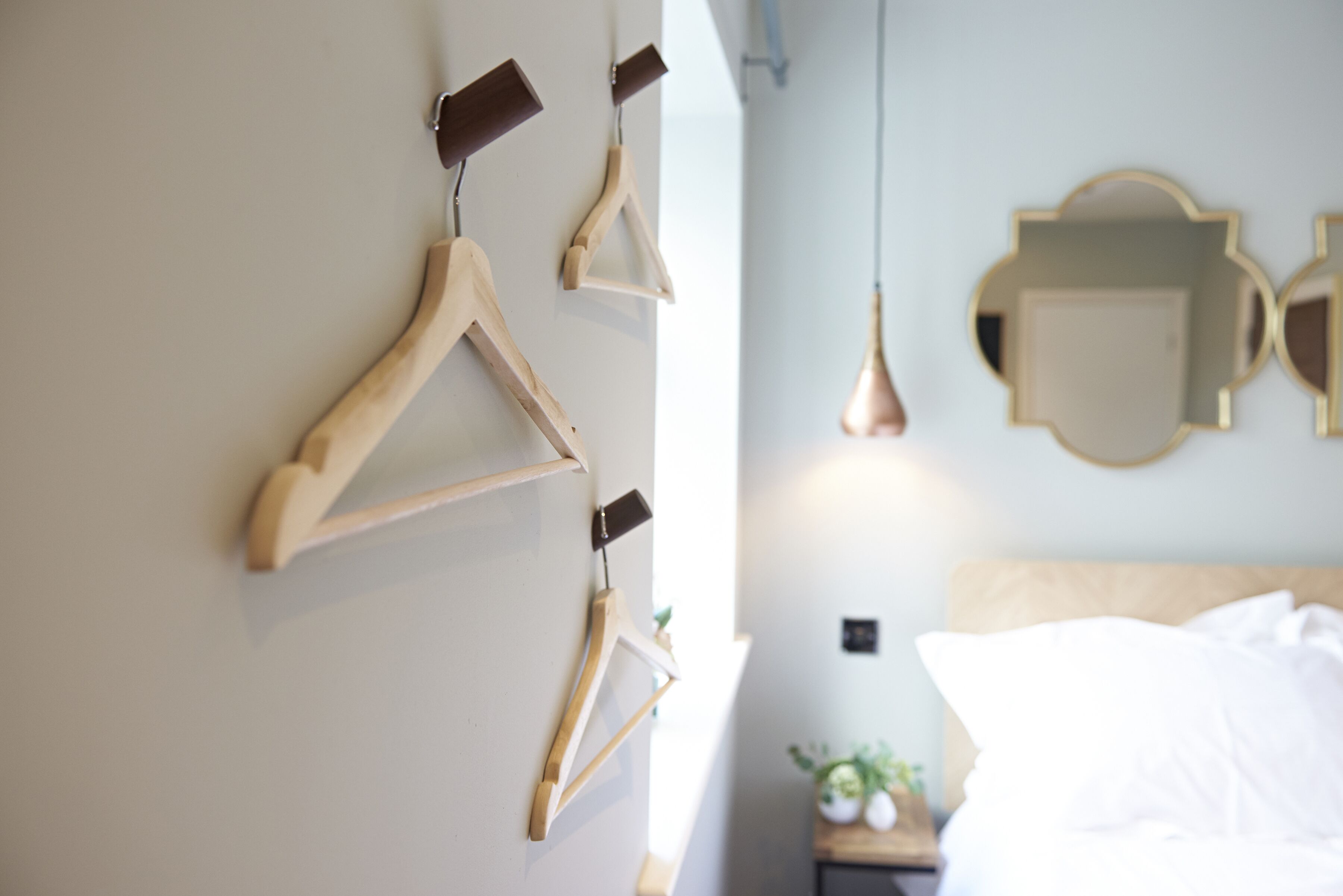 A bedroom with a bed, a nightstand, and a wall-mounted mirror.