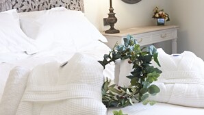 A neatly made bed with white linens and a decorative wreath. - Valentinos Restaurant With Rooms (Ripon)
