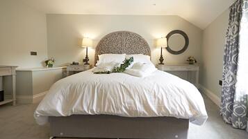 A bedroom with a large bed, two bedside tables, a round mirror, and a nightstand with a lamp.