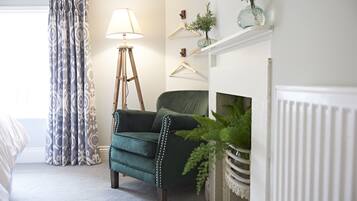 Une pièce avec un fauteuil vert, une lampe sur pied, une cheminée et une plante.