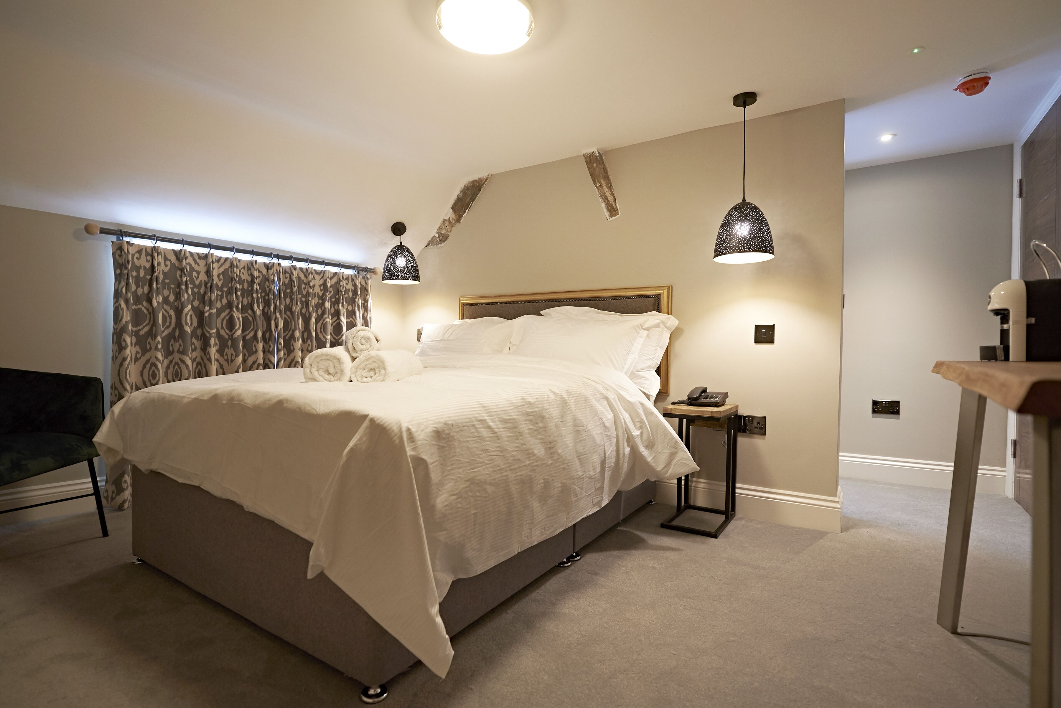 A modern bedroom with a large bed, bedside tables, and a nightstand.