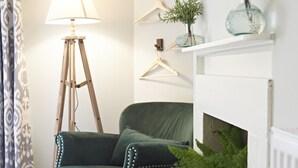 A cozy living room with a green armchair, a floor lamp, a fireplace, and decorative plants. - Valentinos Restaurant With Rooms (Ripon)
