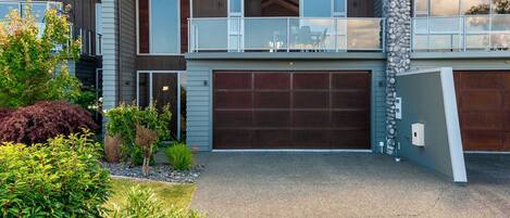 A modern two-story house with a garage, a balcony, and a stone pillar.
