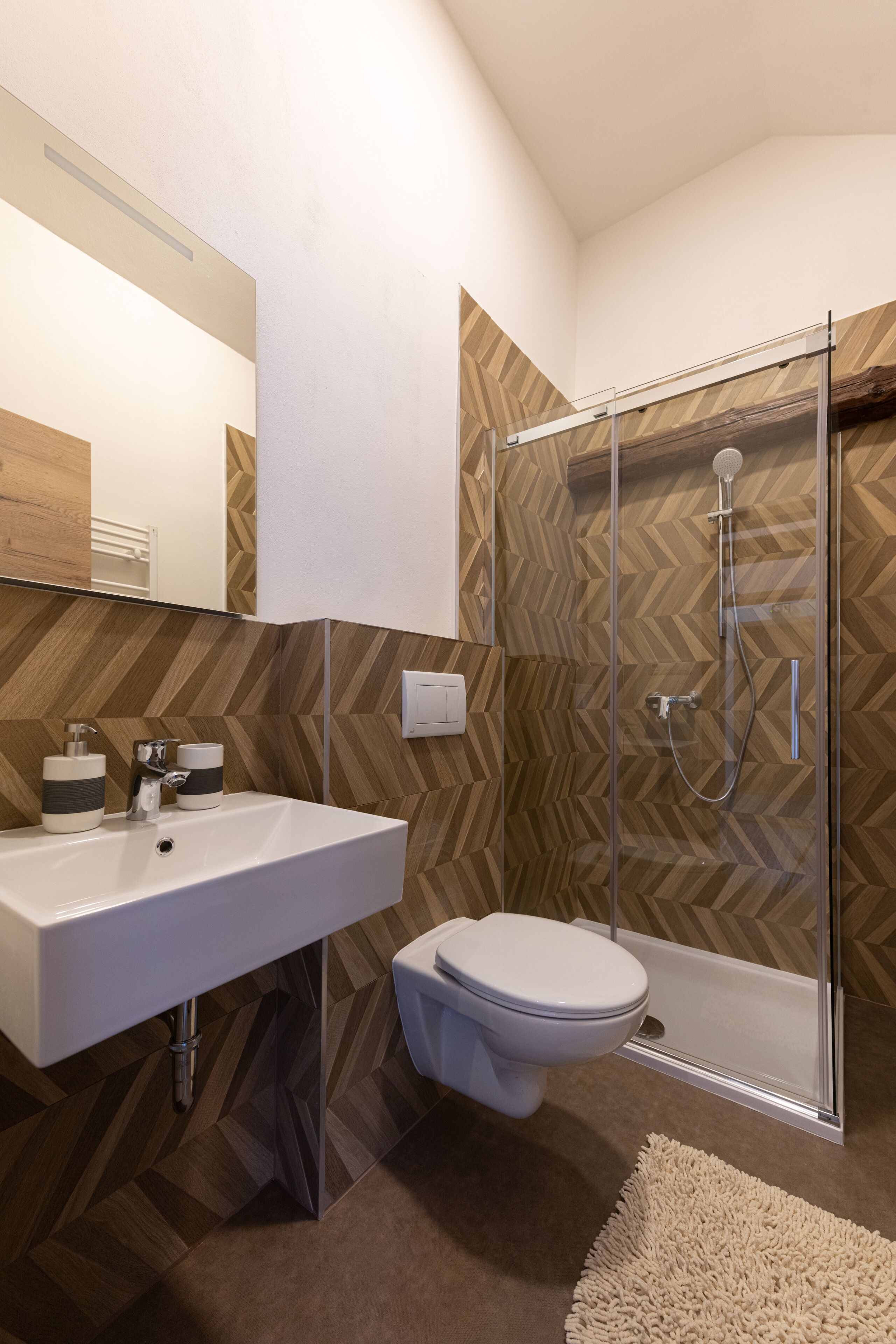 A modern bathroom with a white sink, a toilet, and a glass-enclosed shower.