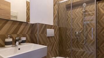 A modern bathroom with a white sink, a toilet, and a glass-enclosed shower.