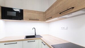 A modern kitchen with a built-in microwave, a sink, and wooden cabinetry. - Apartsee Wellness Plzeň (Plzen)
