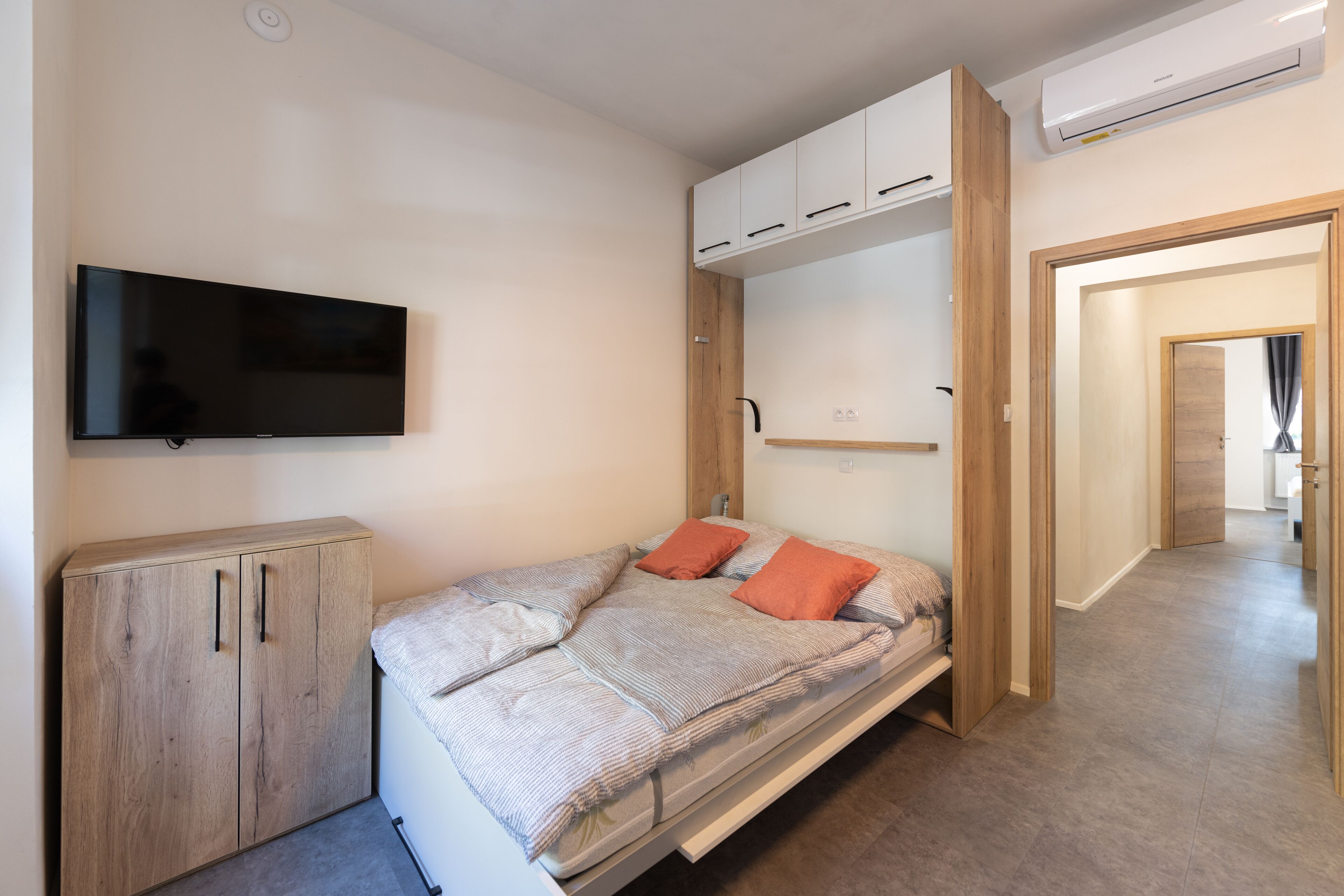 Un dormitorio con cama, televisión y armarios empotrados.