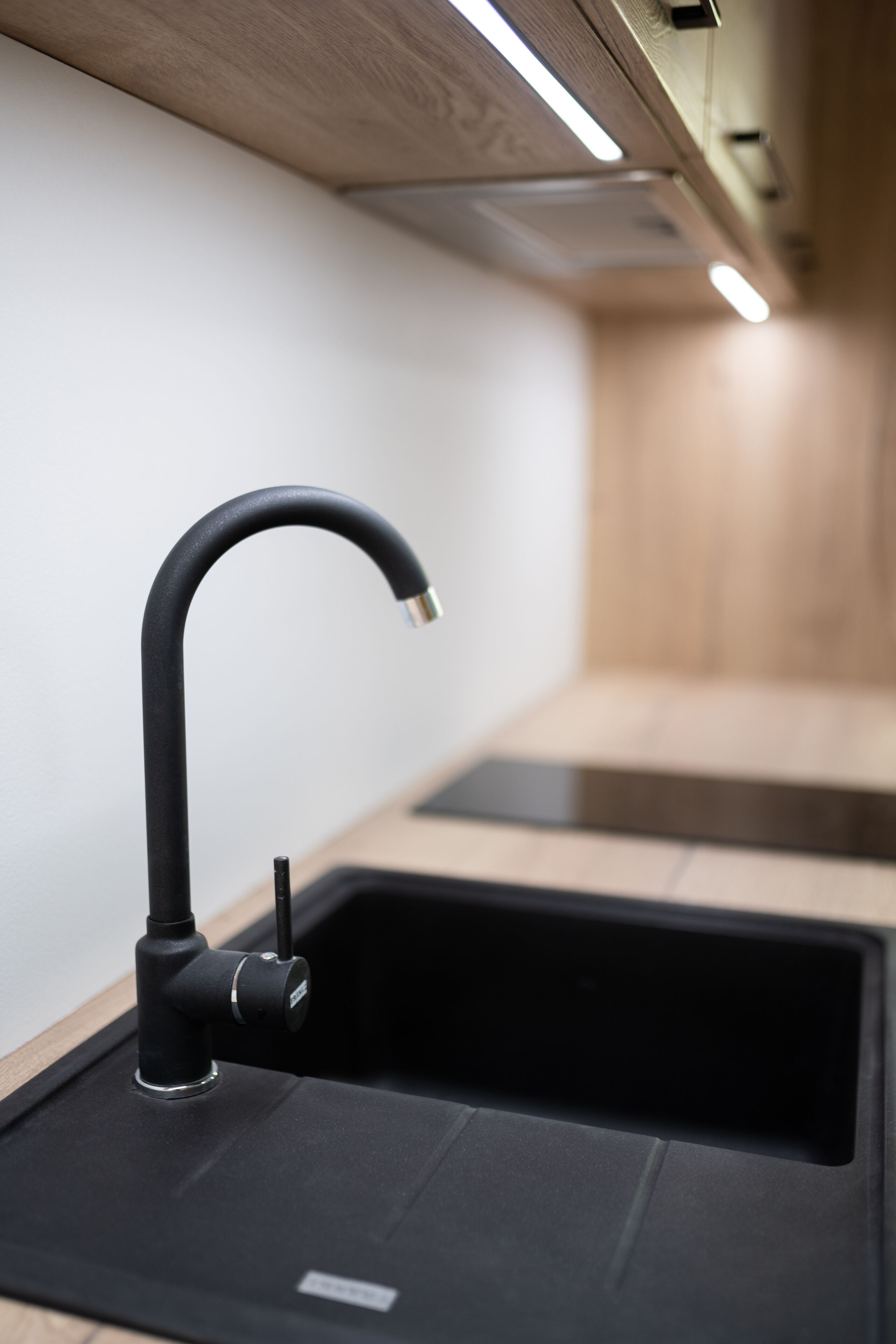 Eine moderne Küche mit einem schwarzen Wasserhahn, Holzschränken und einer schwarzen Arbeitsplatte.