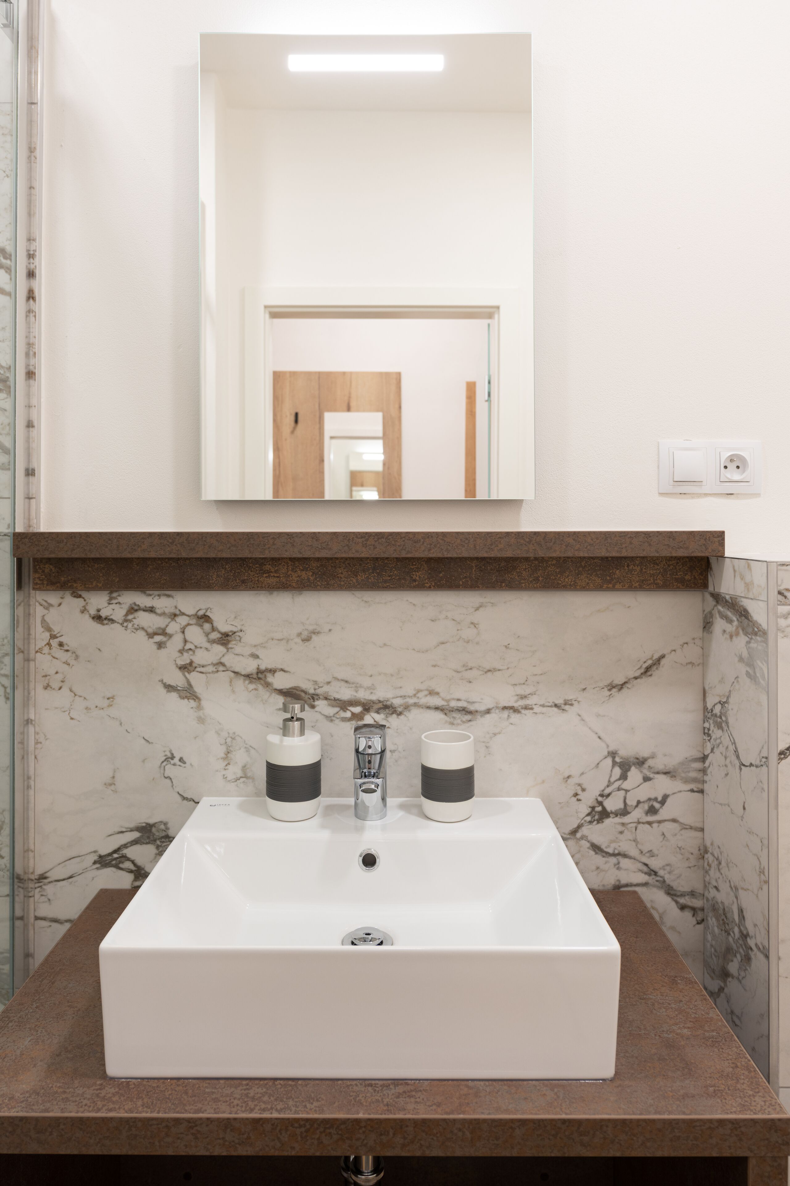 A bathroom with a white sink, two soap dispensers, and a mirror above it.